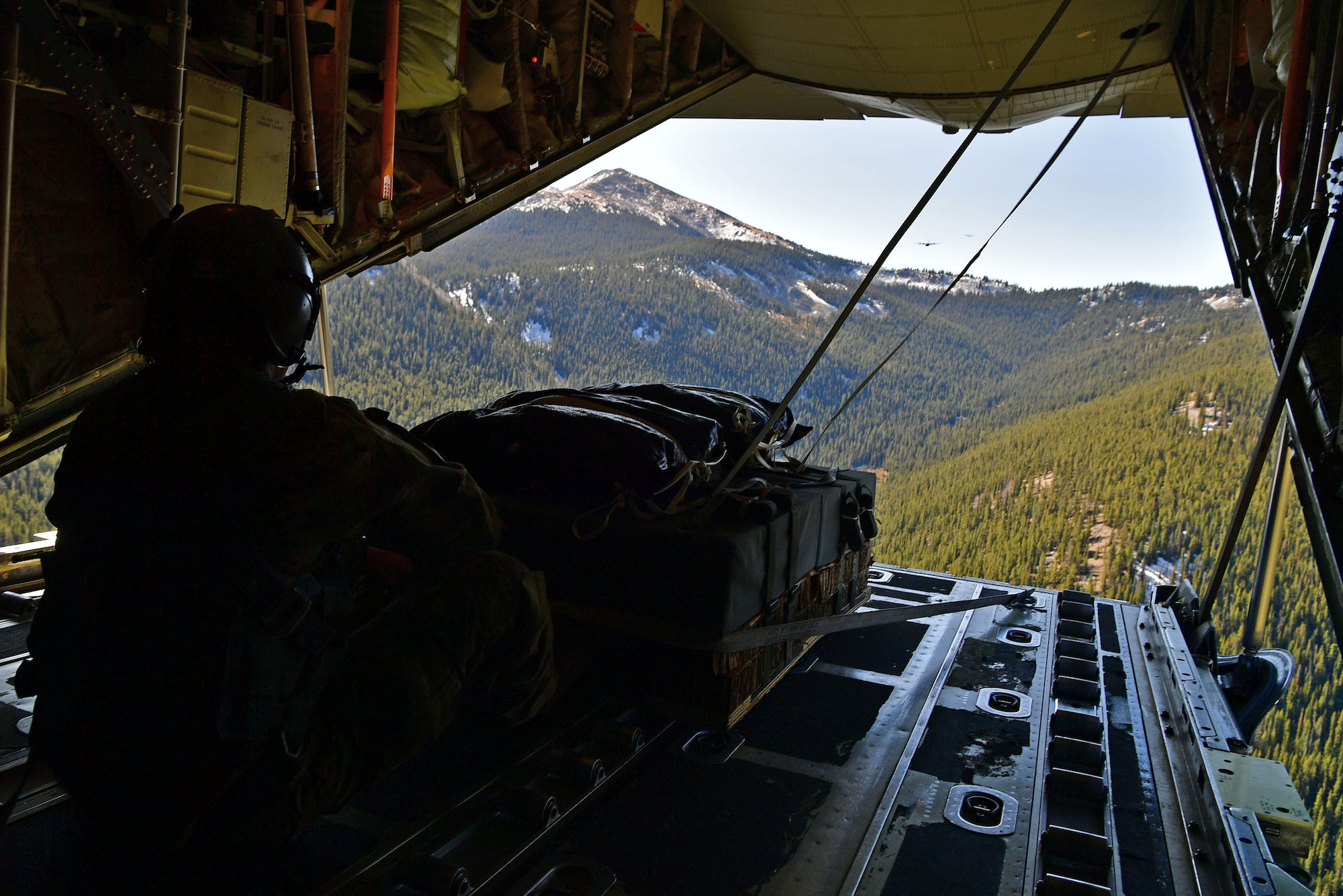 A loadmaster sits on the back of a C-130.