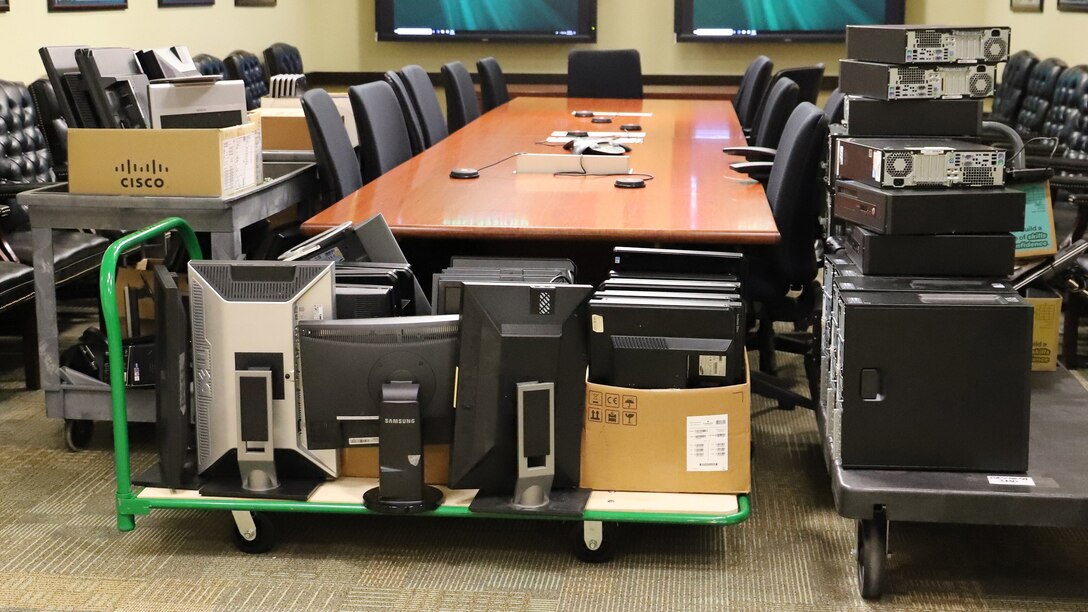 Carts loaded up with computer towers, monitors and laptops are assembled in a conference room