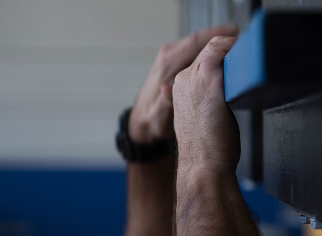 A U.S. Air Force Physical Training Leader from Joint Base Langley-Eustis, Virginia, grips the bars of the Battle Rig at the Air Combat Command gym at JBLE Oct. 17, 2019.