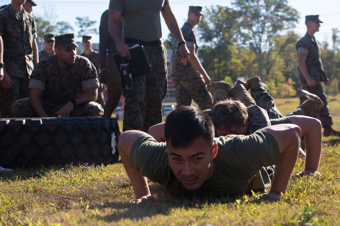 U.S. Marines with Marine Corps Security Force Regiment (MCSFR) prepare to do squad push-ups during a field meet October 18, 2019 at Naval Weapons Station Yorktown, Virginia. The field meet competitions included soccer, flag football, a workout competition, pugil stick bouts, and tug-of-war. The field meet was designed to increase esprit de corps within MCSFR by creating a competitive environment for Marines. (U.S. Marine Corps photo by Sgt. Danielle Prentice/released)