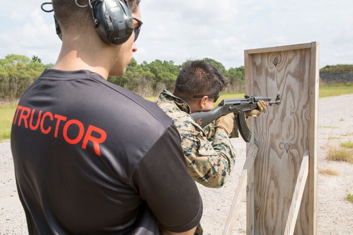 U.S. Marine Corps Sgt. Roger Freckleton, an advanced advisor instructor with Marine Corps Security Cooperation Group, supervises Sgt. Michael Rojas as he fires an AK-47 from behind a barrier during foreign weapons training in Moyock, North Carolina, Sept. 17, 2019.