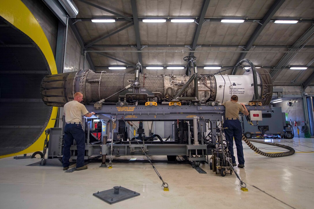 Two airman inspect an aircraft's engine.