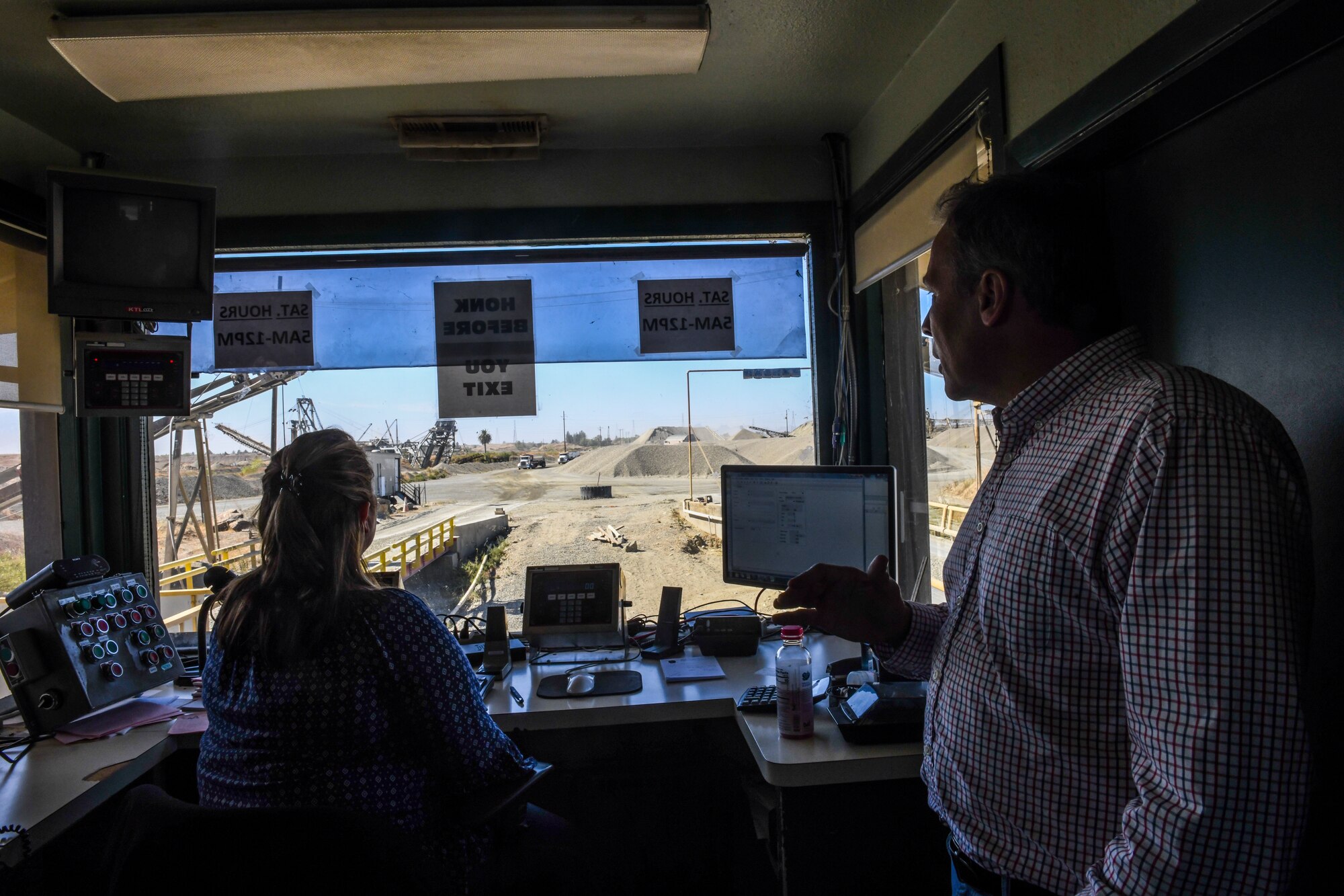 Lana Sharp, Western Aggregates weight master (left), and Lloyd Burns, vice president, communicates with trucks in Marysville, California, Oct. 10, 2019. The weight master logs their information into the system as they leave the construction yard. (U.S. Air Force Photo by Senior Airman Colville McFee)