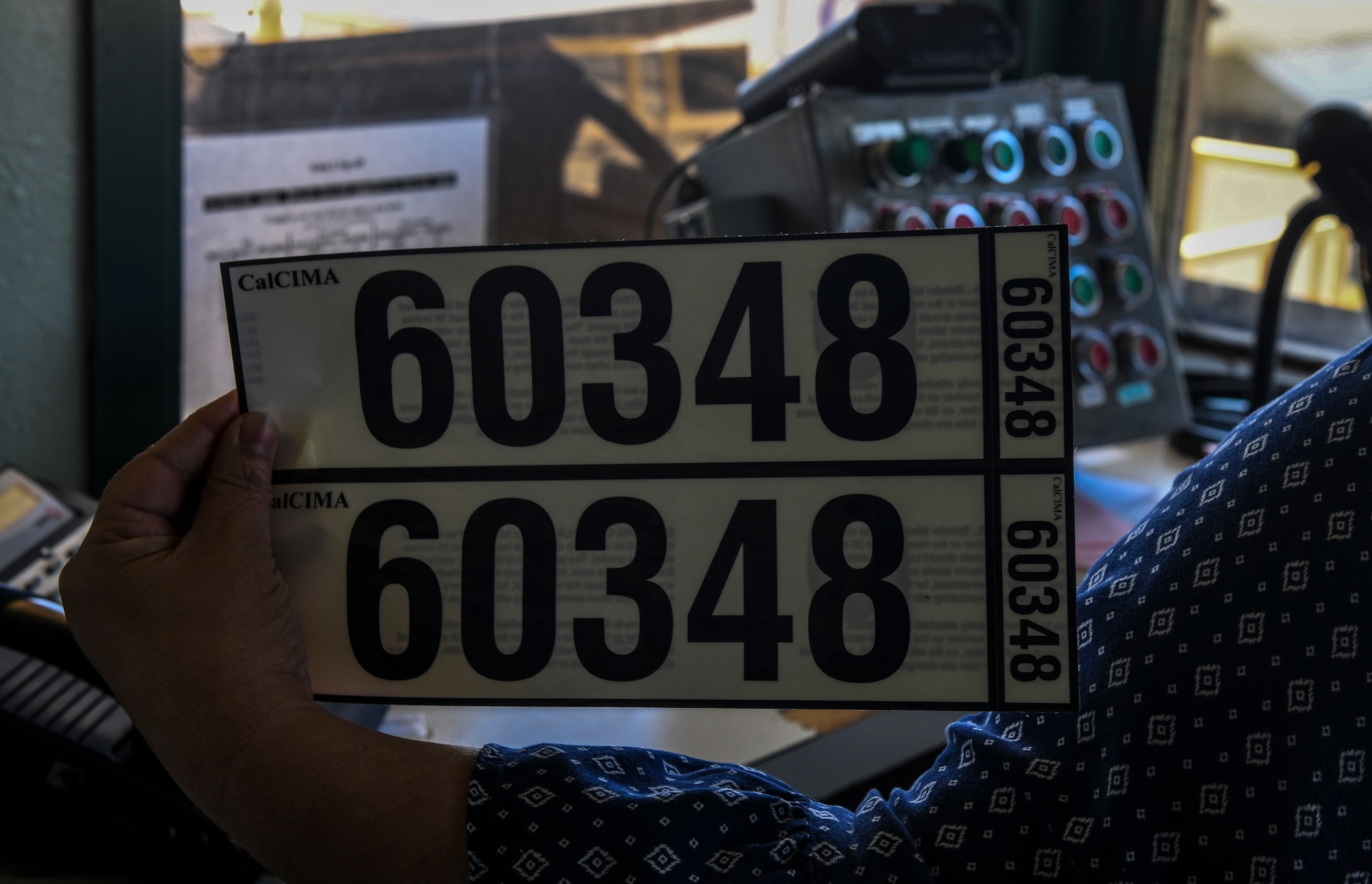 Lana Sharp, Western Aggregates weight master, holds the five digit decal sticker at the weight station in Marysville, California, Oct. 10, 2019. The decal can be located on the truck for identifying who owns the truck. (U.S. Air Force Photo by Senior Airman Colville McFee)