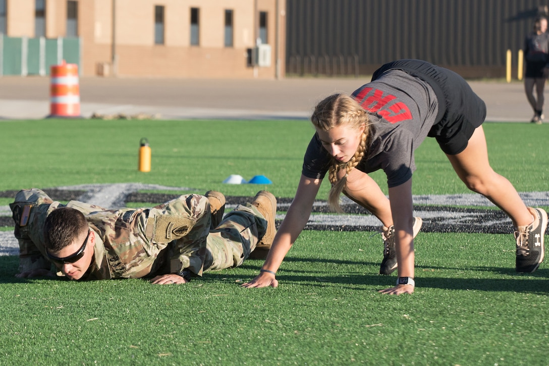 A college student and soldier exercise on a field.