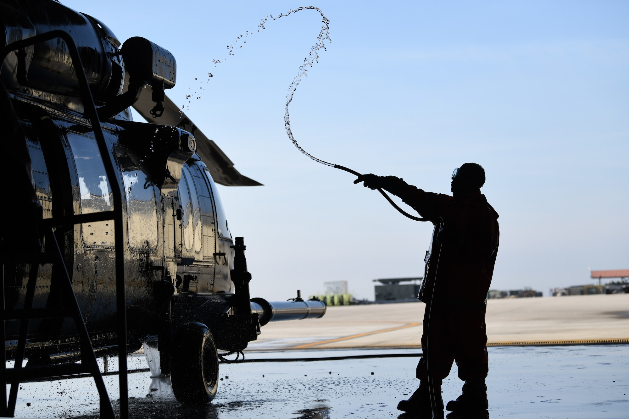 U.S Air Force Airman 1st Class Michael Becerra, an instrument flight control systems specialist from the 31st Aircraft Maintenance Squadron, uses a hose to wash an HH-60G Pave Hawk helicopter at Aviano Air Base, Italy, Oct. 22, 2019. The wash was a part of an aircraft reconstitution checklist, to remove any debris from sandy conditions within desert AORs. (U.S. Air Force photo by Airman 1st Class Ericka A. Woolever).