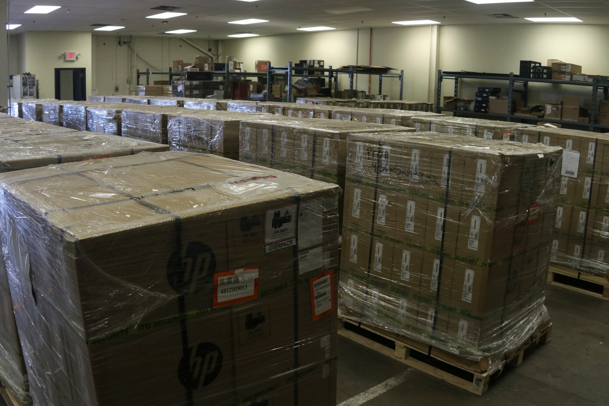Photo shows multiple pallets with boxed laptops in a storage unit.