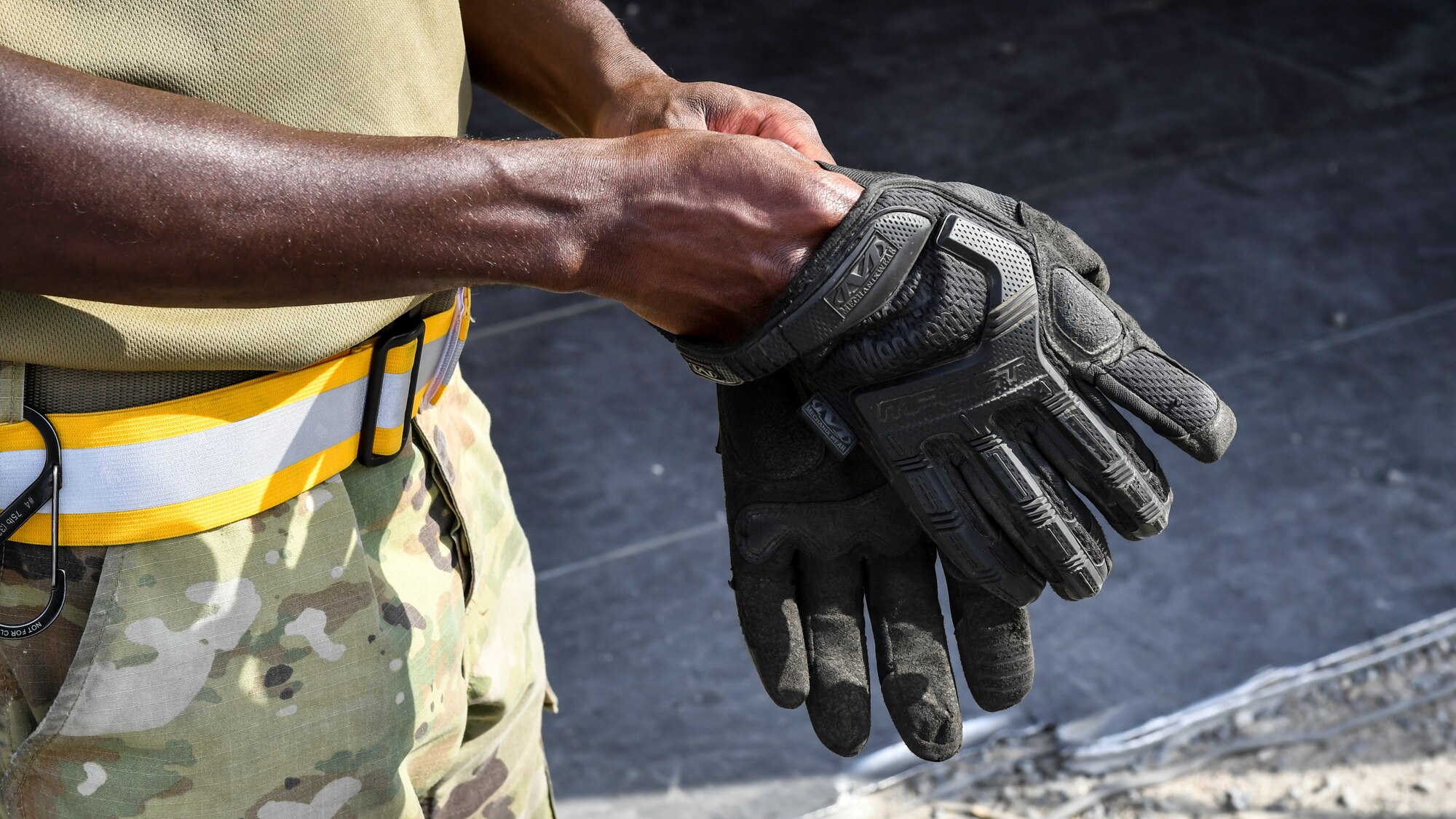 Staff Sgt. Earl Devaughn, 386th Expeditionary Logistics Readiness Squadron aerial port cargo processing representative, puts on work gloves before handling cargo at Ali Al Salem Air Base, Kuwait, Oct. 17, 2019. Port Dawgs use a variety of personal protective equipment to guarantee safety and mission readiness, to include ear and eye protection, gloves, steel toe boots and reflective belts
