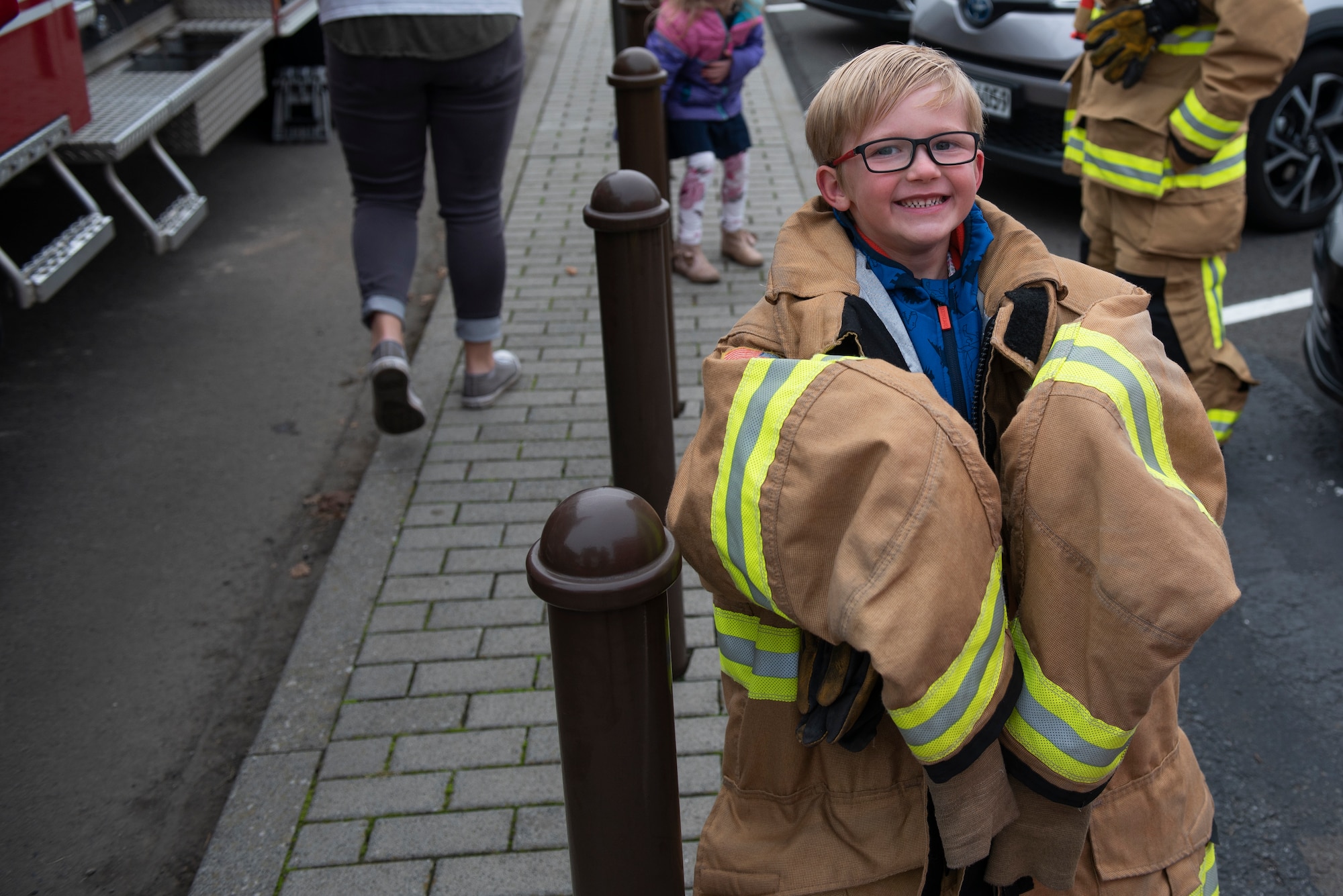 A Spangdahlem Elementary School student wears the protective coat of a Spangdahlem Air Base firefighter at SPES on Spangdahlem Air Base, Germany, Oct. 23, 2019. Students tried on fire gear and learned how firefighters don equipment in a matter of seconds. (U.S. Air Force photo by Airman 1st Class Alison Stewart)