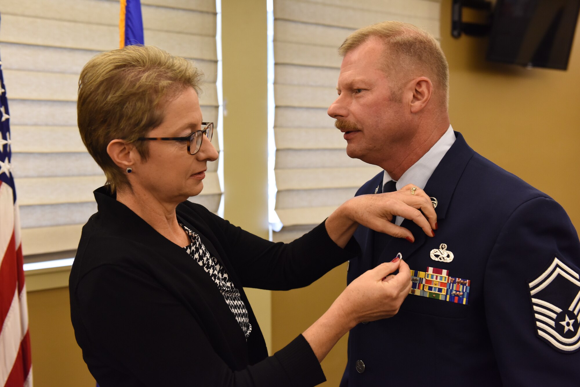 Lynne Szydel, wife of 911th Aircraft Maintenance Squadron Specialist Flight Chief Senior Master Sgt. John A. Szydel, affixes a retiree pin to her husband’s uniform at the Pittsburgh International Airport Air Reserve Station, Pennsylvania, Oct. 5, 2019.