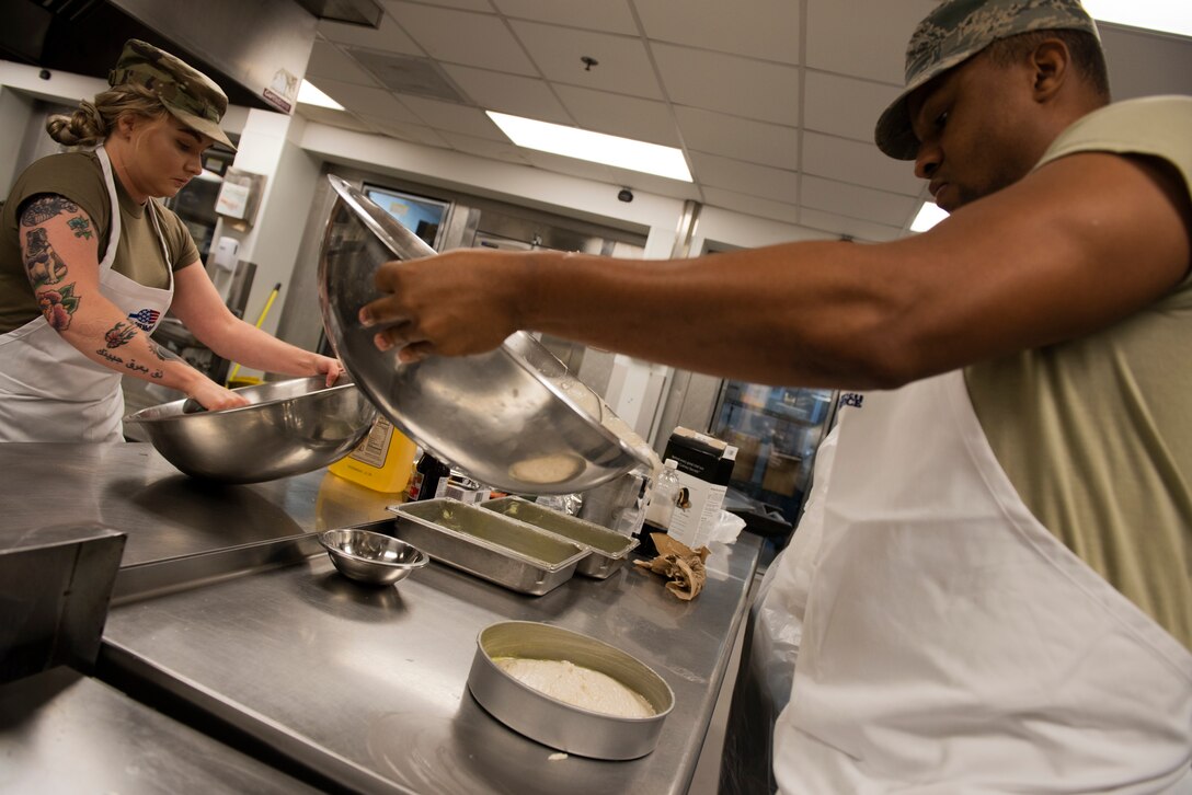 Staff Sgt. Ardella Biser, left, 23d Force Support Squadron (FSS) fitness shift leader, and Staff Sgt. Cameron Morrow, 23d FSS honor guard trainer, pour cake batter during a Scary Cake Bake-Off Oct. 23, 2019, at Moody Air Force Base, Ga. The event, hosted by the 23d FSS, pitted two teams against each other to bake and design a Halloween-themed cake. In the end, the three judges declared Ight Imma Head Out the winning team. (U.S. Air Force photo by Airman Elijah M. Dority)