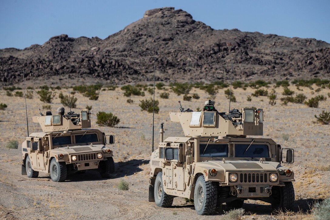 A Marine looks through binoculars while sitting in a military vehicle.