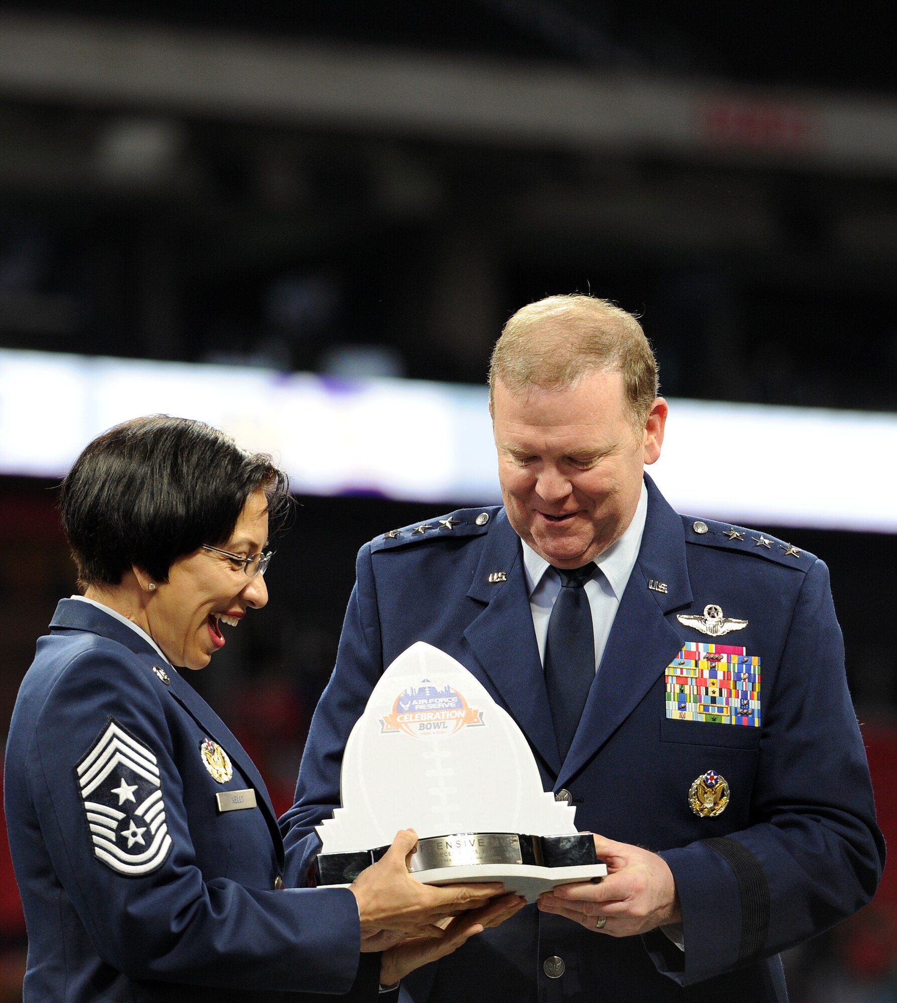 U.S. Air Force Chief Master Sgt. Ericka Kelly, Command Chief, Air Force Reserve Command and U.S. Air Force Lt. Gen. Richard W. Scobee, Commander, AFRC, hold the Offensive Most Valuable Player Award for the Air Force Reserve Celebration Bowl before presenting it to the recipient at the conclusion of the game at Mercedes-Benz Stadium in Atlanta, Georgia, December 15, 2018. (U.S. Air Force photo by Master Sgt. Stephen D. Schester)