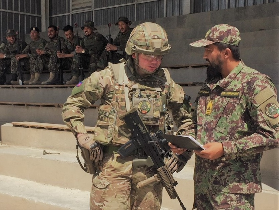 Afghan soldier speaks with British advisor.