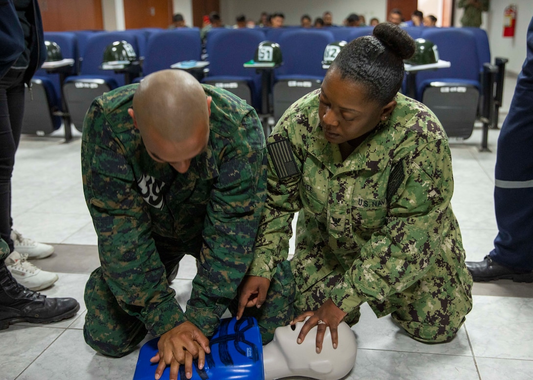 Military medical personnel practice cardiopulmonary resuscitation on  a mannequin.