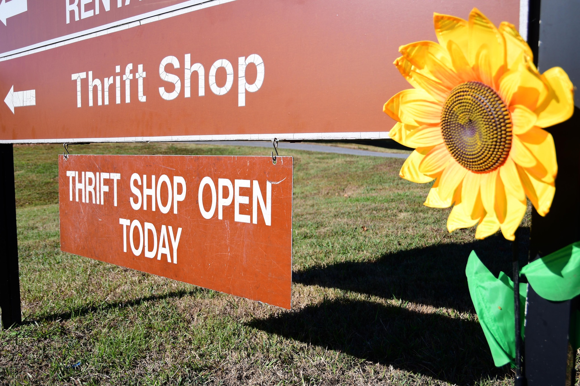 A sign hangs from a directional sign on Dobbins Air Reserve Base, Ga. showing that the base thrift shop is open. The shop is open Thursdays and drill weekend Saturdays from 10 a.m. to 3 p.m. (U.S. Air Force photo/Tech. Sgt. Andrew Park)