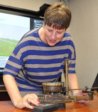 IMAGE: DAHLGREN, Va. (Oct. 24, 2019) – Bonnie Roman, Naval Surface Warfare Center Dahlgren Division (NSWCDD) management analyst, examines a World War I bombsight. The aircraft course-setting bombsight is one of the few surviving examples of the many bombsights tested at Naval Proving Ground Dahlgren in the 1920s and 1930s. Roman – who serves as the NSWCDD Integrated Budget Planning and Execution System lead - is the command employee featured for October 2019 NSWCDD National Disability Employment Awareness Month. “Most people I have interactions with don’t realize that I am deaf in my right ear since I have adapted to losing my hearing as a child,” said Roman. “When I am not working, I love to travel to see different scenery throughout the United States and other countries.”