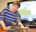 IMAGE: DAHLGREN, Va. (Oct. 24, 2019) – Bonnie Roman, Naval Surface Warfare Center Dahlgren Division (NSWCDD) management analyst, examines a World War I bombsight. The aircraft course-setting bombsight is one of the few surviving examples of the many bombsights tested at Naval Proving Ground Dahlgren in the 1920s and 1930s. Roman – who serves as the NSWCDD Integrated Budget Planning and Execution System lead - is the command employee featured for October 2019 NSWCDD National Disability Employment Awareness Month. “Most people I have interactions with don’t realize that I am deaf in my right ear since I have adapted to losing my hearing as a child,” said Roman. “When I am not working, I love to travel to see different scenery throughout the United States and other countries.”