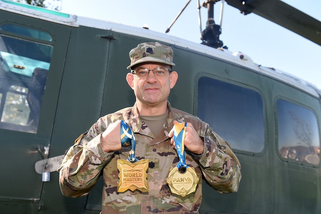 Lt. Col. Pete Caragher, Deputy G-3, 85th U.S. Army Support Command, holds two medals that he won in a Brazilian Jiu-Jitsu competition one is a 2014 World Masters gold medal and the other is a first place gold medal from the 2013 International Brazilian Jiu-Jitsu Federation Championship.