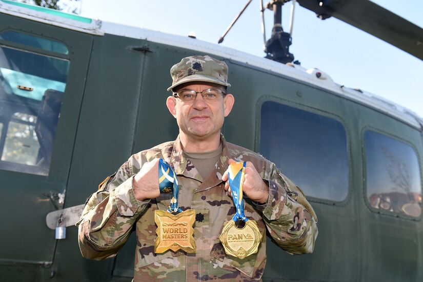 Lt. Col. Pete Caragher, Deputy G-3, 85th U.S. Army Support Command, holds two medals that he won in a Brazilian Jiu-Jitsu competition one is a 2014 World Masters gold medal and the other is a first place gold medal from the 2013 International Brazilian Jiu-Jitsu Federation Championship.