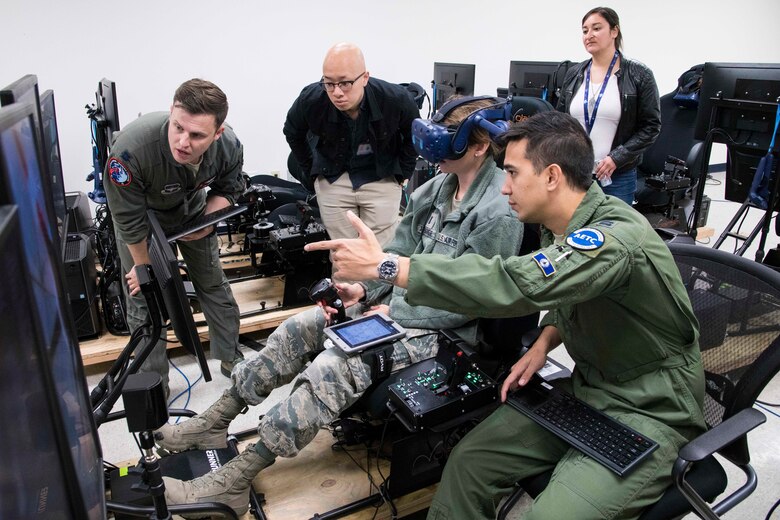 U.S. Air Force Capt. Orion Kellogg, Pilot Training Next instructor pilot, provides feedback to a future student of PTN version three during a virtual reality flight with NASA officials at Joint Base San Antonio-Randolph, Texas, Oct. 22, 2019, as part of a collaborative research agreement between PTN and NASA. The partnership will focus on biometric data collection and the application of emerging technology into PTN curriculum that will innovate the student pilot learning environment. (U.S. Air Force photo by Sean M. Worrell)