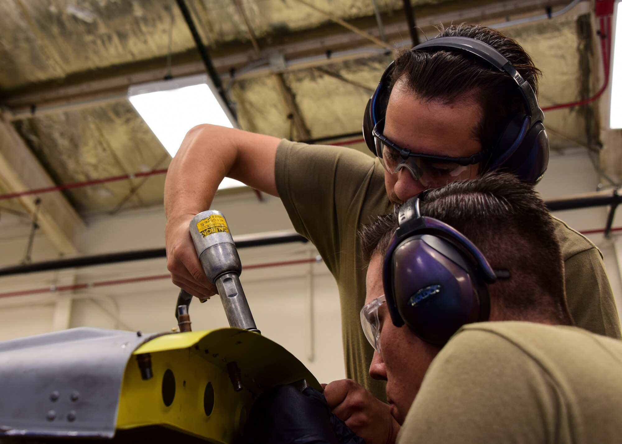 Airmen work on piece of sheet metal