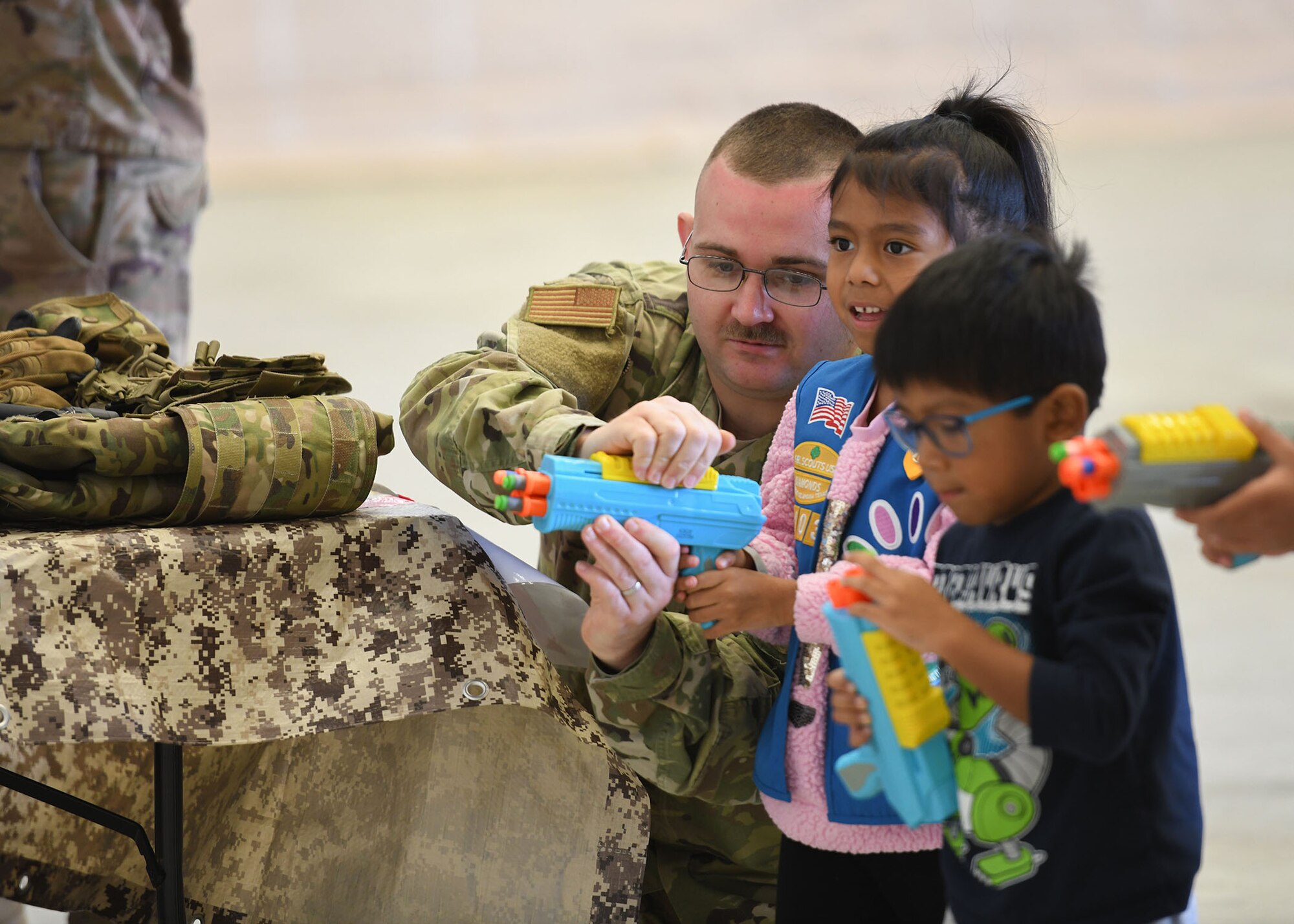 An Airman helps children with a toy.