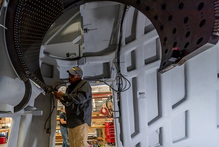 Photo of Tobyhanna employee installing gun port shield guide rails.