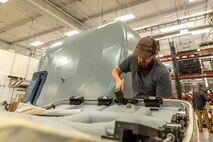 Photo of Tobyhanna employee installing the locking mechanism for the weather shield door.