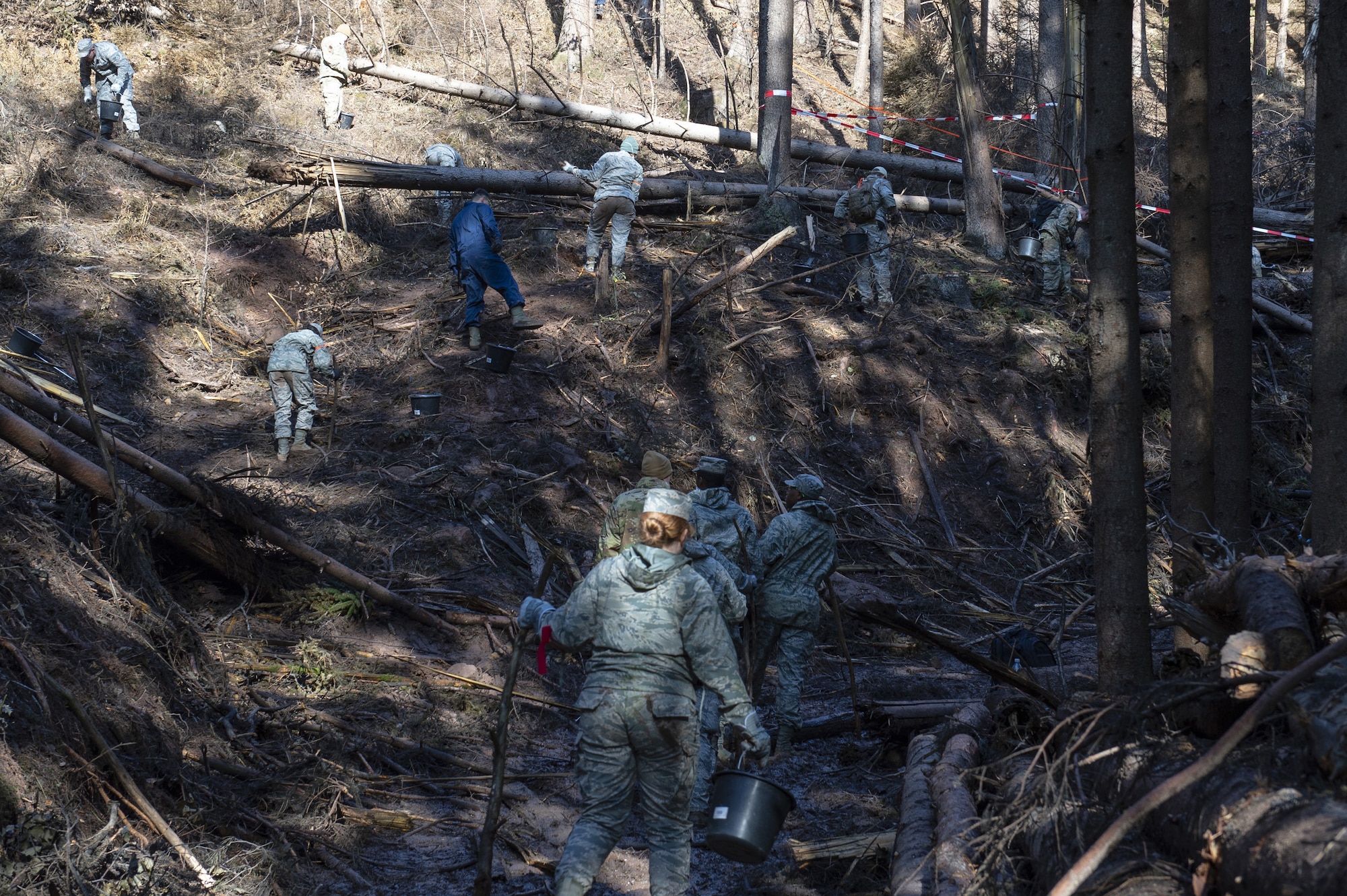 Airmen have worked in the dense wooded area digging through thick vegetation to recover F-16 parts.
