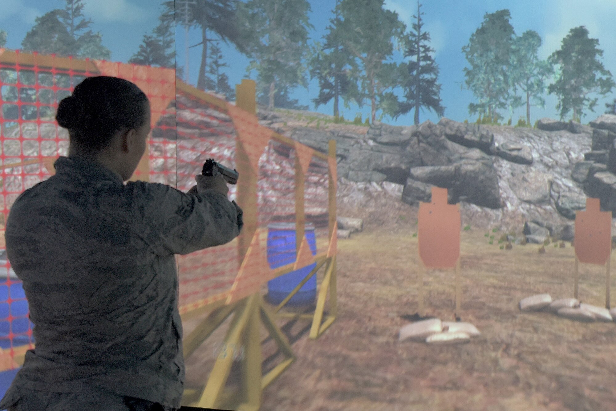 Airman 1st Class Katelyn Powers, 100th Security Forces Squadron response force member, fires her weapon at the targets in the Firearms Training Simulator at RAF Mildenhall, England, Oct. 21, 2019. The simulator comes with more than 300 different scenarios which can be manipulated by the instructor depending on the response of the student. (U.S. Air Force photo by Senior Airman Benjamin Cooper)