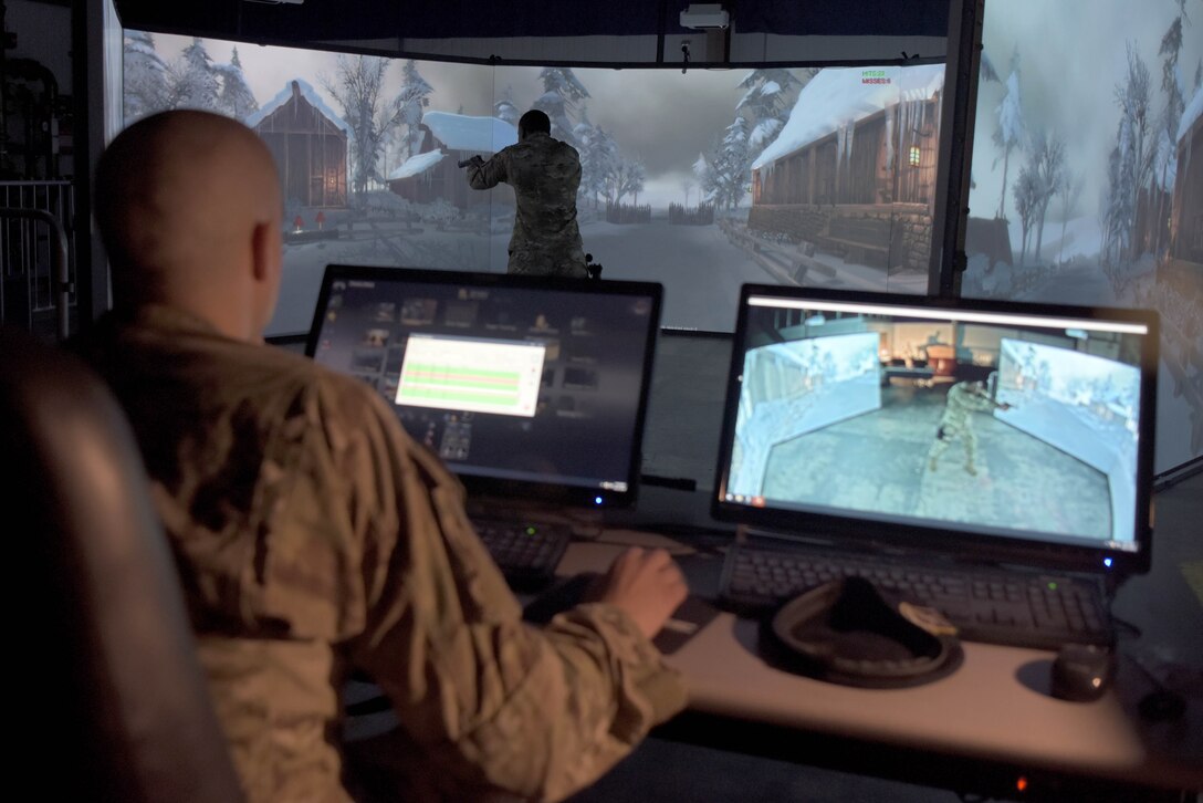 Staff Sgt. Brian Walker, 100th Security Forces Squadron instructor, observes a student engaging targets in the Firearms Training Simulator at RAF Mildenhall, England, Oct. 21, 2019. Instructors can use the system to count how many shots were fired and where those shots impacted to improve a students performance and responses. (U.S. Air Force photo by Senior Airman Benjamin Cooper)