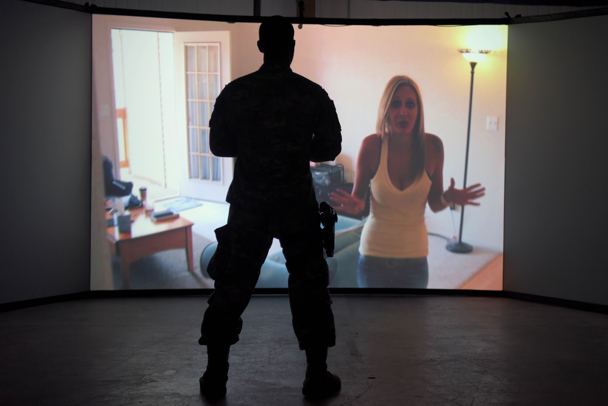 Senior Airman Branden Wilborn, 100th Security Forces Squadron response force member, interviews a subject during a scenario in the Firearms Training Simulator at RAF Mildenhall, England, Oct. 21, 2019. New scenarios can be created for training that are specific to that particular installation. (U.S. Air Force photo by Senior Airman Benjamin Cooper)
