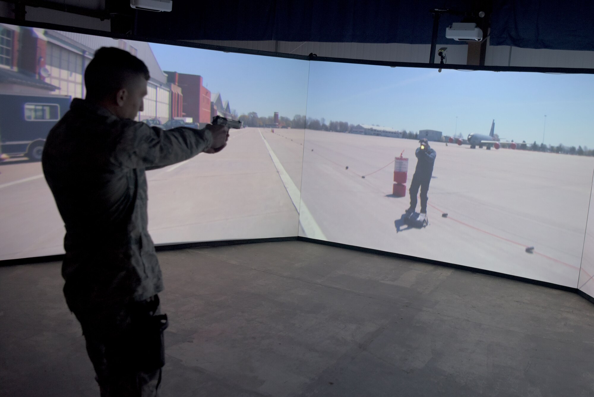Airman 1st Class Clay Marentis, 100th Security Forces Squadron response force member, fires his simulated weapon during a scenario in the Firearms Training Simulator at RAF Mildenhall, England, Oct. 21, 2019. New scenarios can be created for training that are specific to that particular installation. (U.S. Air Force photo by Senior Airman Benjamin Cooper)
