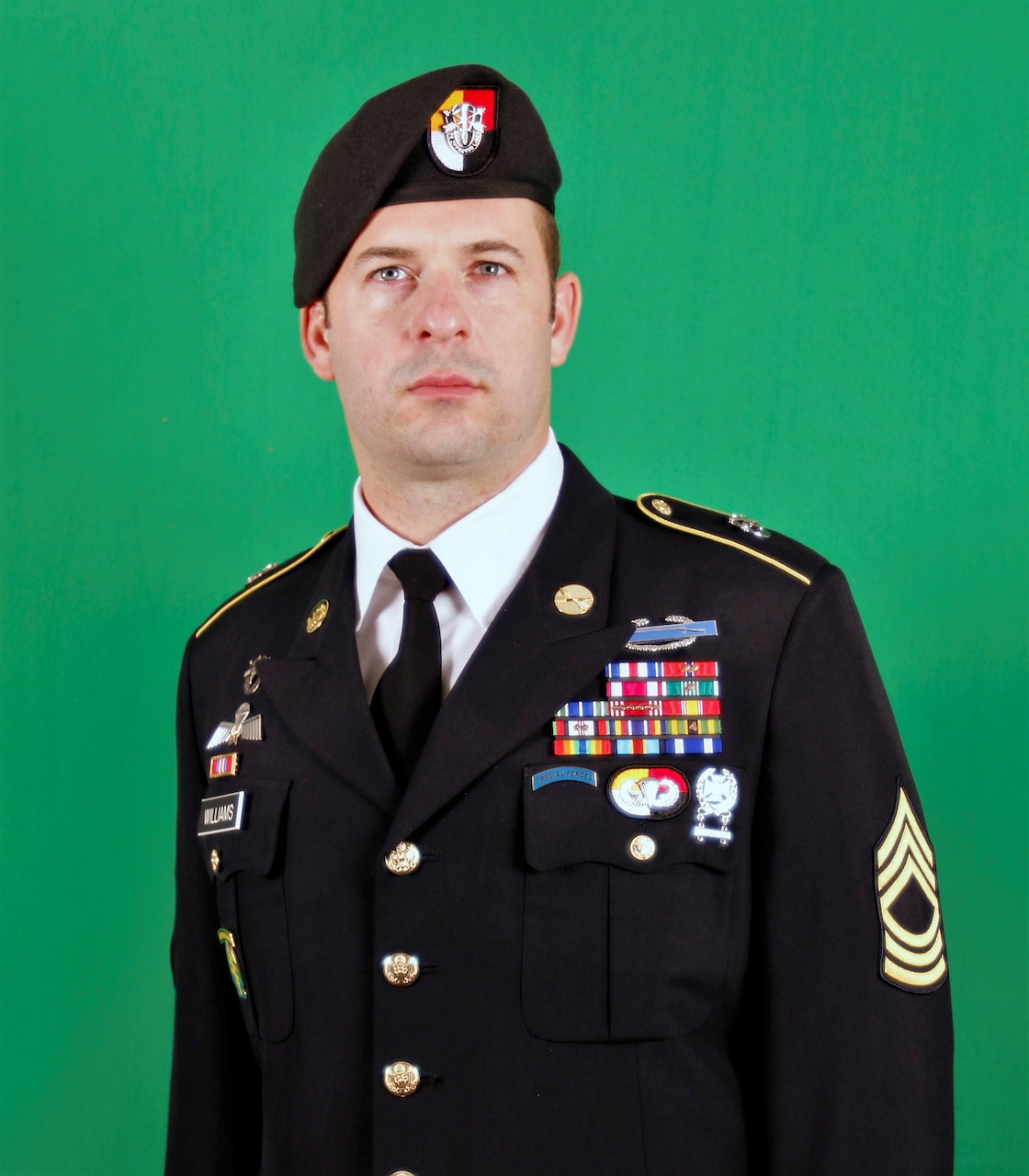 Man wearing dress uniform and beret for an official photo.