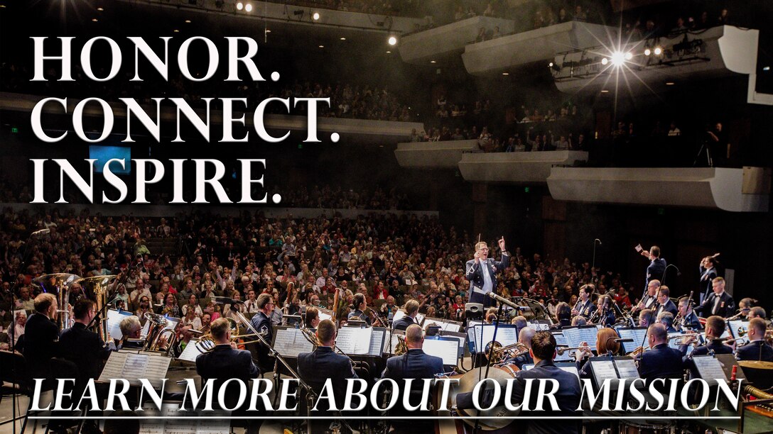 A Concert Band performs in an auditorium packed with people in patriotic garb, featuring vocalists reaching out to the audience and smoke from stage effects lingering in the air.