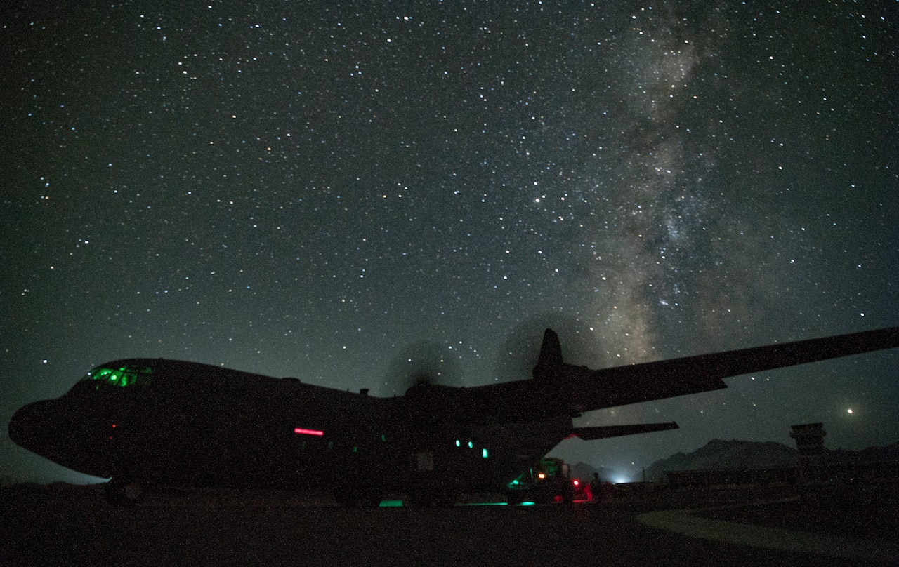 Tactical aircraft sits on a runway against the backdrop of a starry sky.