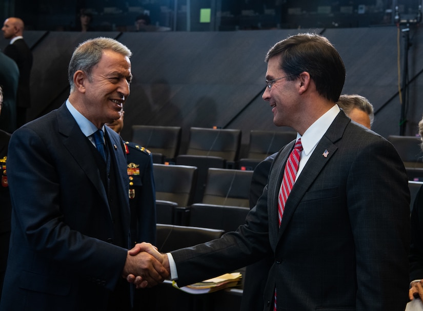 Two men in suits shake hands.