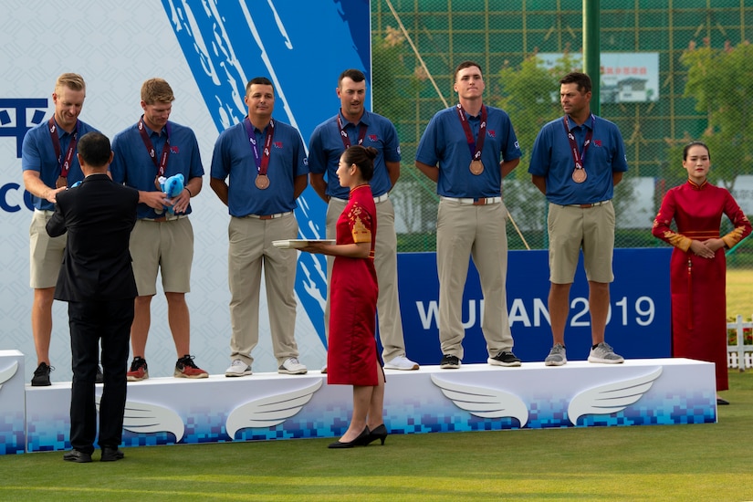 Six men receive bronze medals during a presentation ceremony.