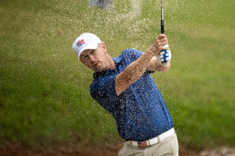 Sand sprays as a golfer hits out of a bunker.