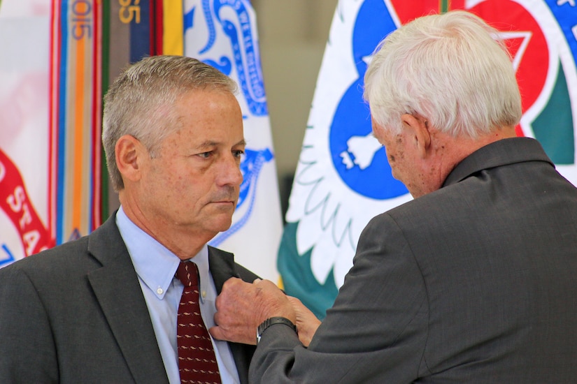 Retired Master Army Aviator George Downer affixes the Senior Executive Service pin to his son, Geoff Downer’s lapel. The U.S. Army inducted Downer, director of the U.S. Army Aviation and Missile Command’s Special Programs (Aviation), into Senior Executive Service during an Oct. 18 appointment ceremony at Joint Base Langley-Eustis, Virginia.