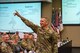 man in army uniform points up in the air.