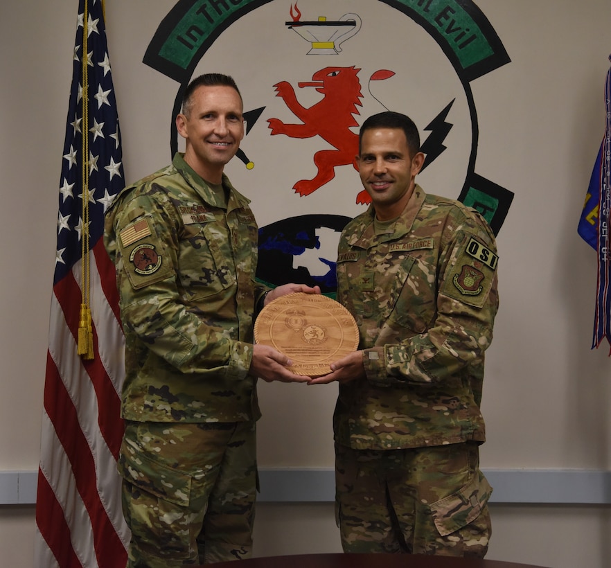 Col. Michael C. Mentavlos, right, the Individual Mobilization Augmentee to the AFOSI Region 6 Commander, was recently selected to represent the Air Force Reserve and AFOSI on the Defense and Security Issues Committee (DEFSEC). Here, Senior Master Sgt. Alan Frank presents him with a token of appreciation from the men and women of the 24th Expeditionary Field Investigations Squadron at the 24 EFIS Change of Command ceremony at Al Udeid Air Base, Qatar, Aug. 15, 2019. (U.S. Air Force photo by Staff Sgt. Ashley L. Gardener)