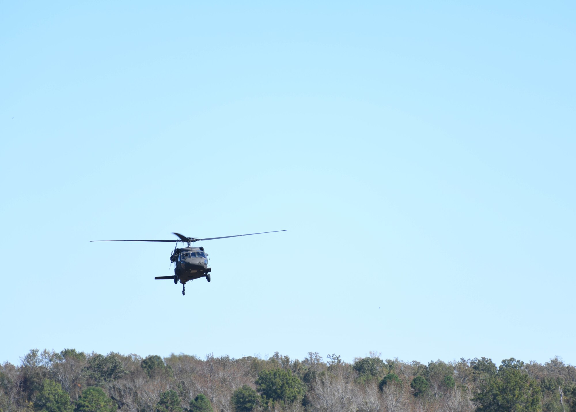 A UH-60 Black Hawk flies above a field.