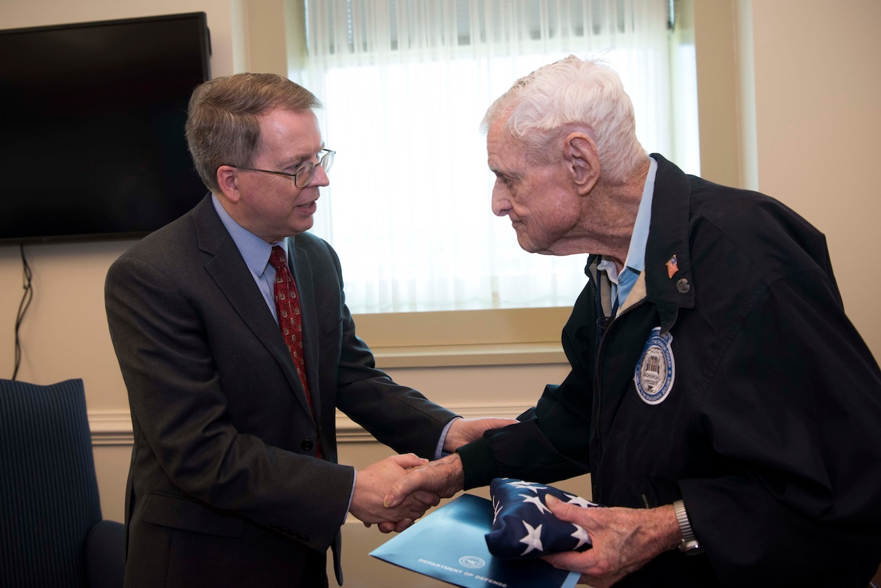Deputy Defense Secretary David L. Norquist shakes hands with an elderly man