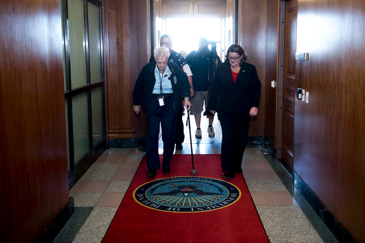 A man and a woman walk through a hallway.