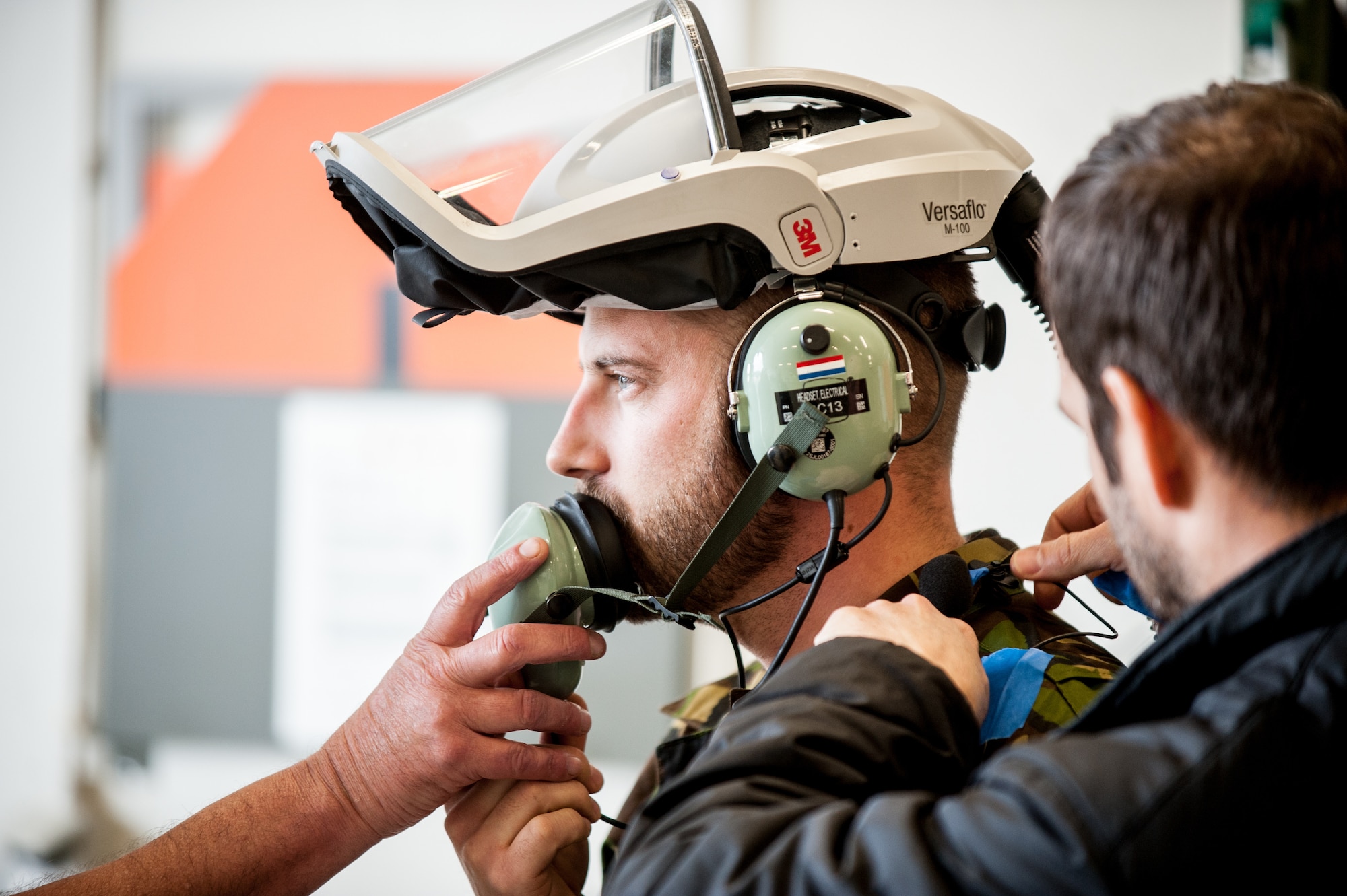 A Dutch bioenvironmental engineer attaches microphones to an F-35 maintainer prior to a testing session, led by acoustics experts in the Air Force Research Laboratory’s 711th Human Performance Wing. Other members of the international team test air quality, all in efforts to provide a report about the safety of personnel and F-35s inside the hardened aircraft shelter. (Photo courtesy of Royal Netherlands Air Force)