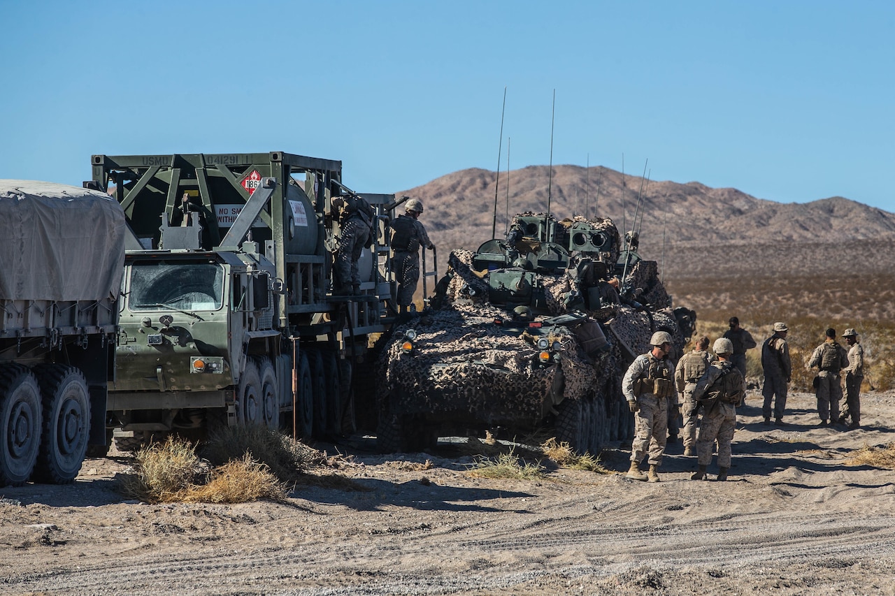 Marines stand near some equipment in the desert.
