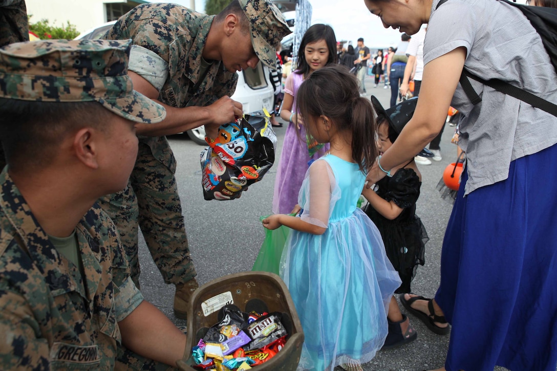 子どもたちにお菓子を配る海兵隊員。キャンプ・シュワブでは10月26日（土）、一足早いハロウィーン・パーティがＵＳＯ（米国慰問団）で開催され、200人以上の海兵隊のボランティアと400人以上の地元の親子が会場を埋め尽くしました。