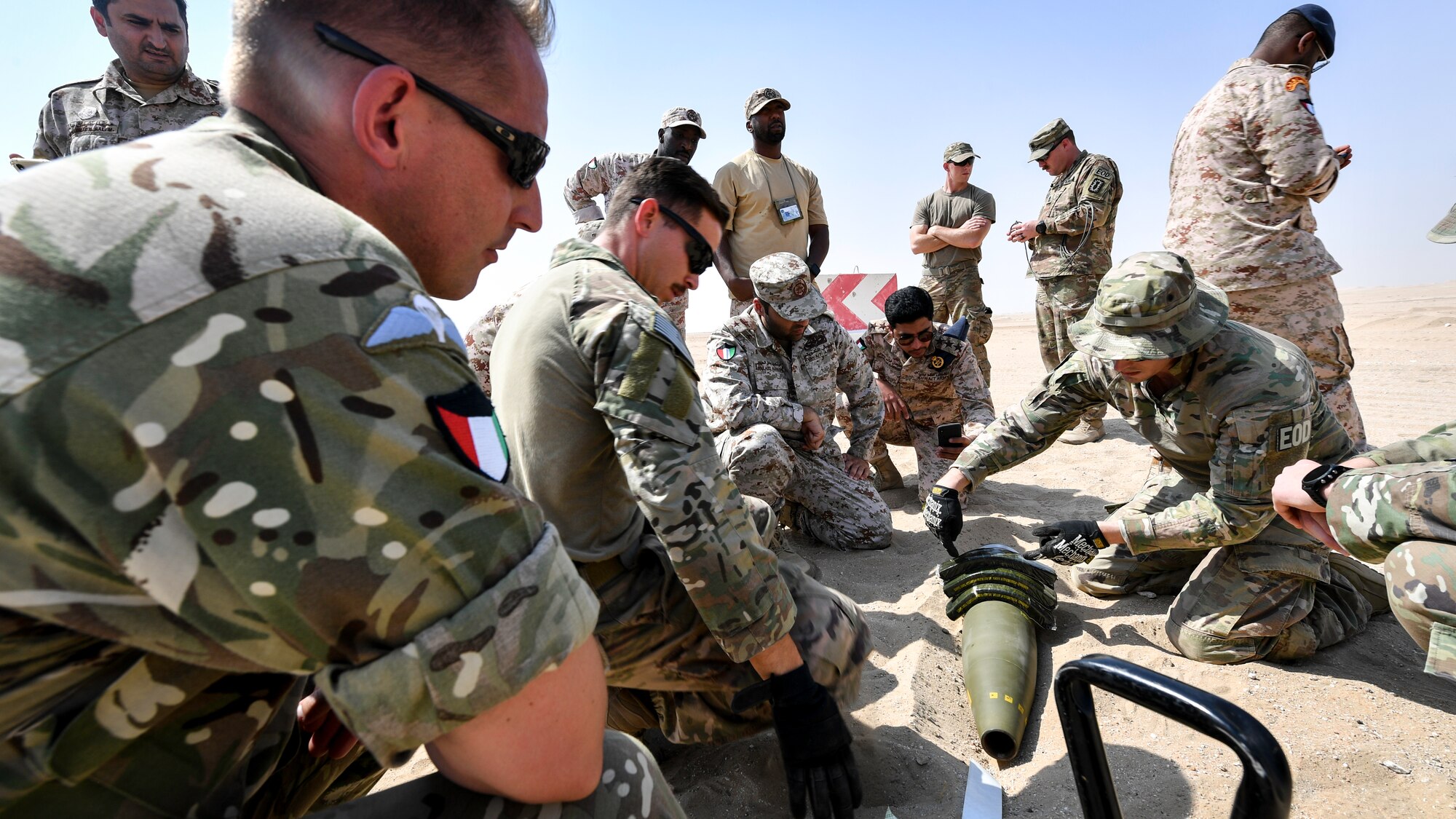 U.S. Army Sgt. 1st Class Jesse Harris, 744th Ordnance Company operations sergeant, demonstrates proper placement of C-4 high explosives on to a 155MM insensitive high explosive round before a munitions disposal training at the Udari Range, Kuwait, Sept. 30, 2019. C-4’s high cutting ability when detonated makes it the ideal explosive to use in disposal or controlled detonations of insensitive high explosive rounds.